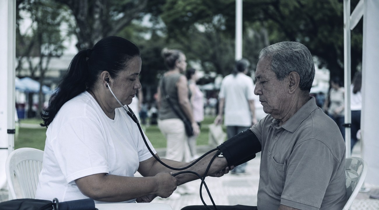 Profissional de saúde aferindo a pressão de um senhor na feira de saúde